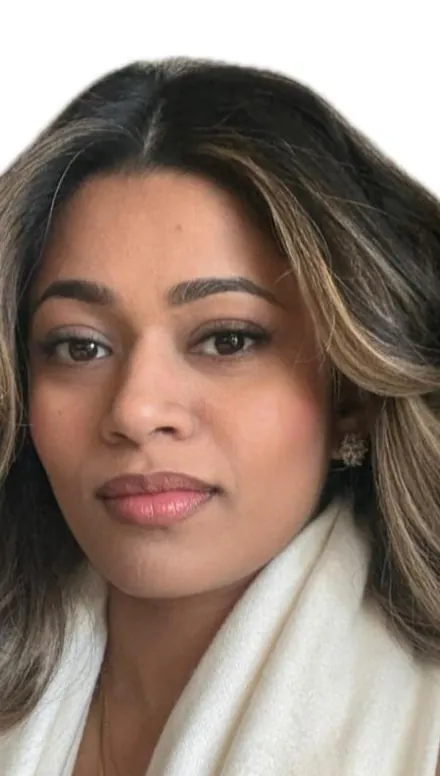 Portrait of Oshi Dias, honey-blonde ribbons in her dark hair, wrapped in a cream knit